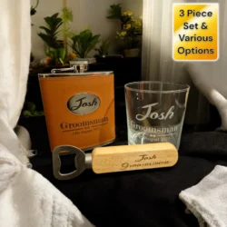 A three-piece set consisting of a flask, a glass, and a bottle opener. The flask is wrapped in a brown leather cover with a metal plate engraved with the name 
